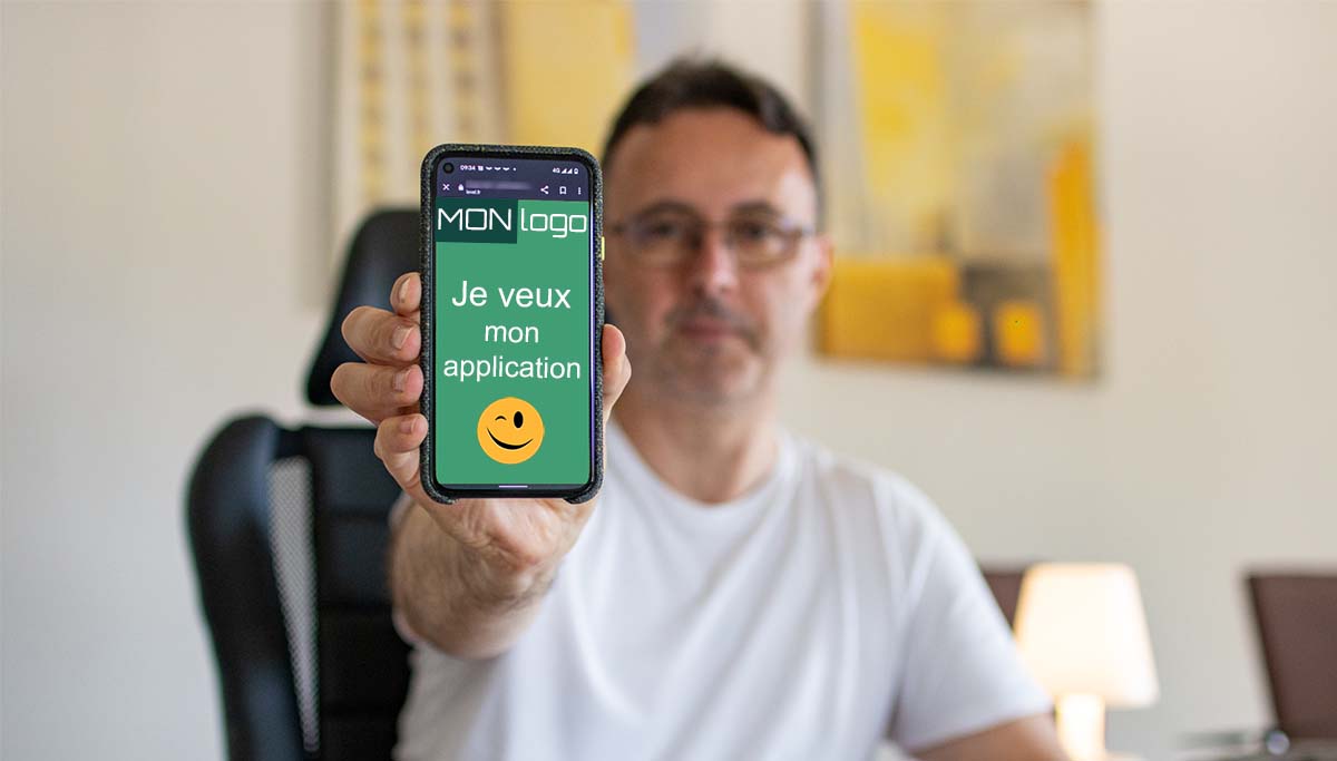 Damien Forner, gérant de l'agence Index LD, tient un smartphone indiquant "je veux une application smartphone"